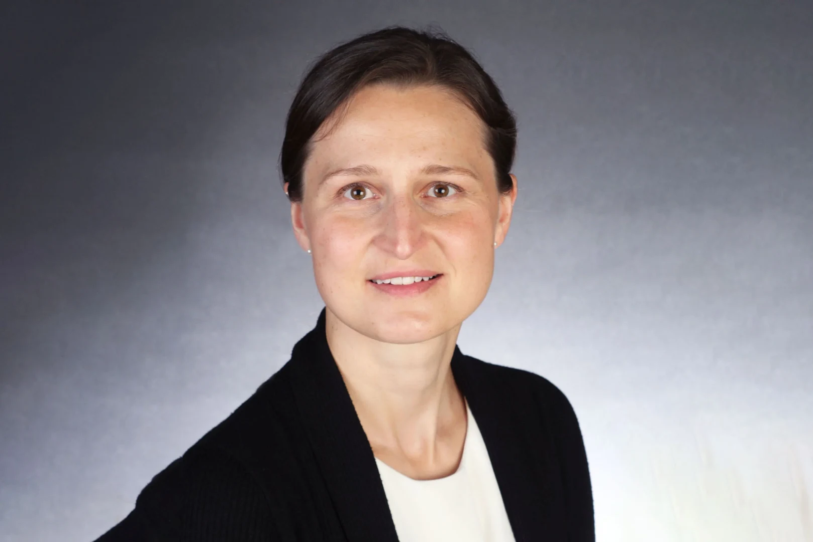 Eine Wissenschaftlerin und ein Wissenschaftler arbeiten hinter einer Glasfassade und mischen Chemikalien mit Großgeräten.