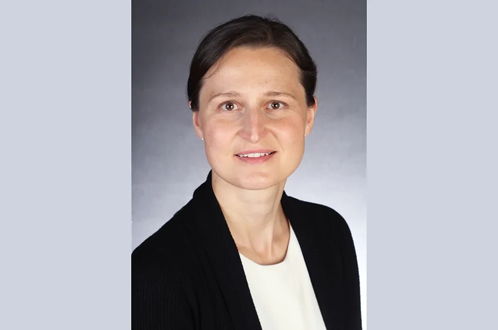 Eine Wissenschaftlerin und ein Wissenschaftler arbeiten hinter einer Glasfassade und mischen Chemikalien mit Großgeräten.